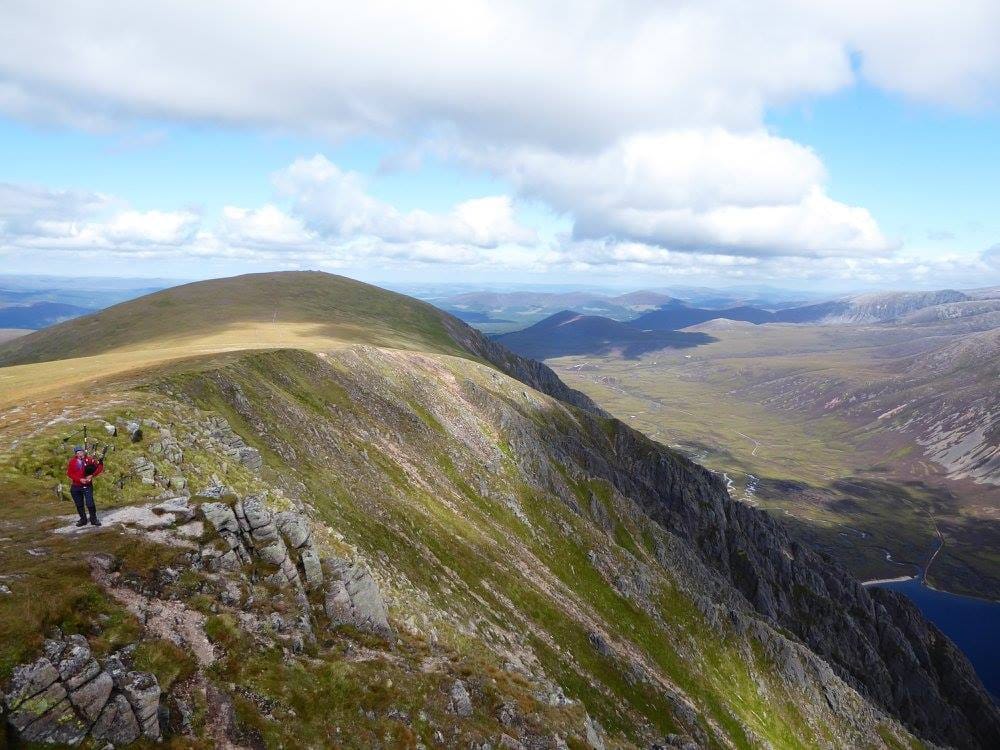 TUNES OF GLORY: A piper plays near the summit of Sgor Gaoith, a fitting backdrop for a final Munro ascent